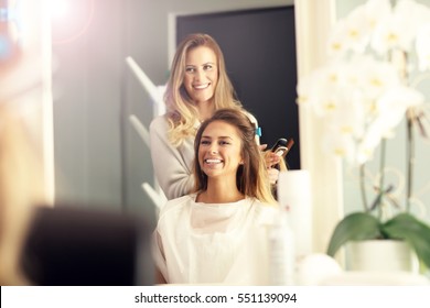 Hairdresser Using Hair Straightener In Studio