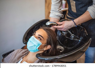 A hairdresser washing the hair to a client. Young woman have hair cutting at hair stylist during pandemic isolation, they both wear protective equipment. Hair stylist washing  - Shutterstock ID 1789943051