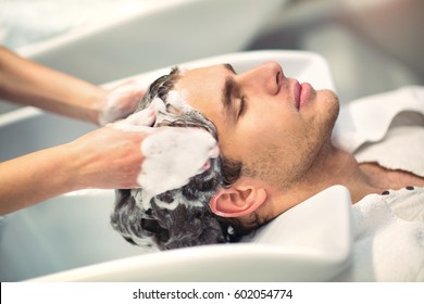 Hairdresser washing hair to her handsome client. Barber at work. Man at barbershop. - Powered by Shutterstock