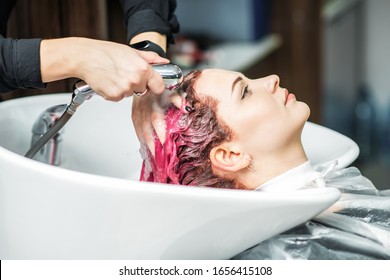 Hairdresser washing pink dyed hair of woman in sink, close up. - Powered by Shutterstock