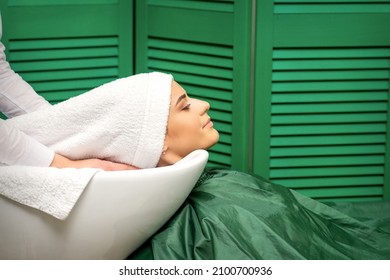 Hairdresser wraps hair of a young caucasian woman in a white towel after washing head in the hairdressing salon. - Powered by Shutterstock