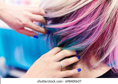 Hairdressers hands in colorful client head and hair after coloring or hair dyeing.