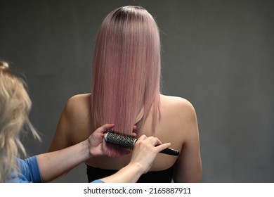 Hairdresser's hands combing model's dyed hair from behind