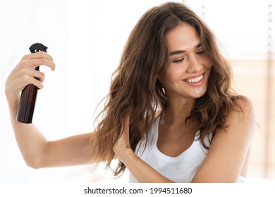 Hairspray Advertisement. Happy Woman Applying Spray On Wavy Hair For Detangling Caring For Herself Standing In Modern Bathroom Indoors. Hairstyling Product For Split Ends - Shutterstock ID 1994511680