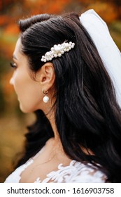 Hairstyle Bride On A Wedding Day. Wavy Black Hair With A Pearl Barrette And An Earring. Details Of The Image On The Wedding Day.