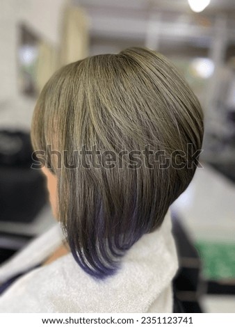 Hairstyles short in the back, long in the front are known as bob pours. Dyed blonde hair with blue highlights.