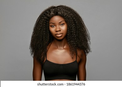 Hairstyling. Beauty fashion portrait of young beautiful african american woman with volume,curly hair against gray background 