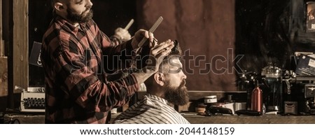 Hairstylist serving client at barber shop. Man visiting hairstylist in barbershop. Bearded man in barbershop. Work in the barber shop. Man hairstylist.