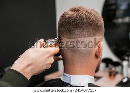 Similar – Image, Stock Photo Barber shaves the temple with cordless trimmer during a short haircut on the sides of the head.