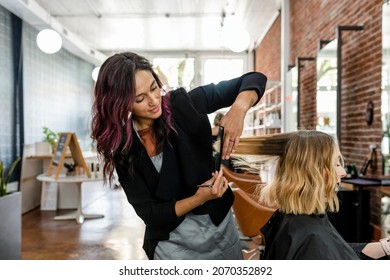 Hairstylist trimming hair of the customer in a beauty salon
