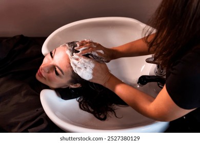 Hairstylist washing adult woman hair with shampoo in spa salon for create hairstyle. Hairdresser hands wash head in barber shop. Concept of customer service at hair salon, haircare. Copy ad text space - Powered by Shutterstock