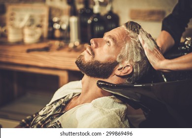 Hairstylist washing client's hair in barber shop - Powered by Shutterstock