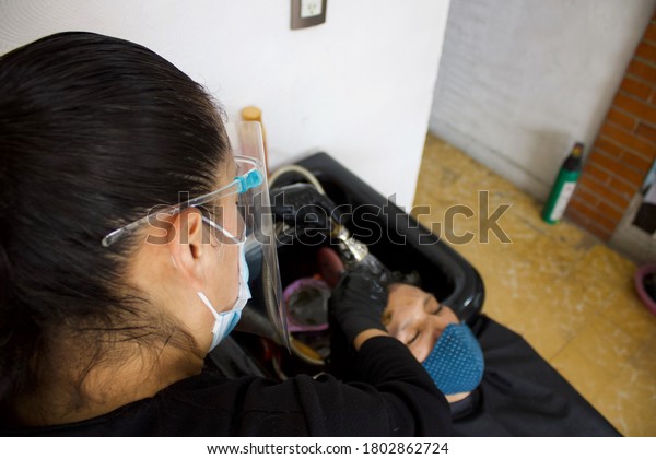 hairstylist wearing\
mask, washing client\'s\
hair