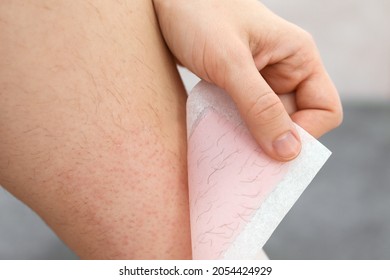 Hairy Legs. Woman Using Beeswax Stripe To Shave Her Leg. Depilation Procedure With Wax, Close Up. Hair Removal Concept.