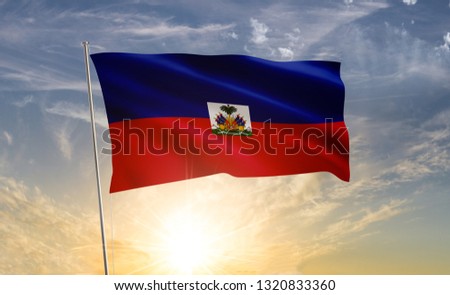 Haiti flag waving in the wind against a blue sky and clouds