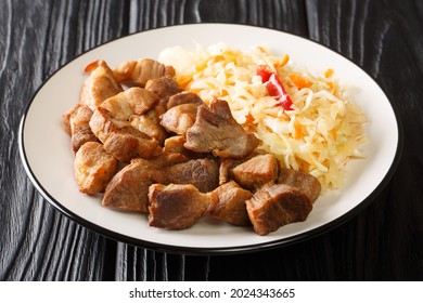 Haitianisches Essen Griot frittierte Schweinekoteletts und Pikliz, Nahaufnahme in einem Teller auf dem Tisch. Horizontal