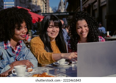 Haitian Woman And Latina Businesswomen Together In An Outdoor Cafe Analyzing On A Laptop With Internet Access