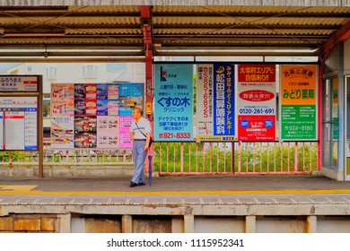 Hakata, Fukuoka, Kyushu, Japan - May 17th ,2015 : Japanese Old Man Stand Alone On The Platform With The Advertisement Billboard And Brochure Vintage Background Inside Local Station In Fukuoka City.