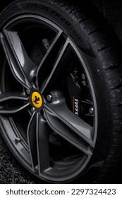 HALE, GB - May 17, 2022: A vertical closeup of a black Ferrari wheel in Hale Village, United Kingdom
