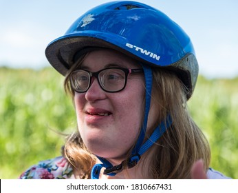 Halendover, Flanders  Belgium - 07 25 2020: Portrait Of A Smiling 38 Year Old Woman With Down Syndrome And A Blue Bike Helmet