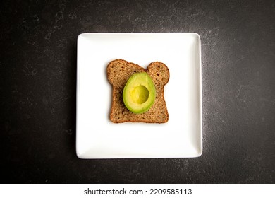 A Half Of An Avacado With No Seed Sitting On A Piece Of Whole Wheat Toast On A White Plate 