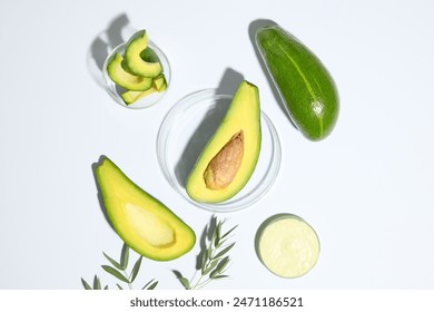 A half of avocado placed on glass petri dish arranged with two petri dishes of avocado cream and avocado slices. Avocados contain a B complex vitamin commonly called biotin - Powered by Shutterstock