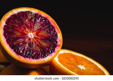 Half blood orange next to orange on a black background