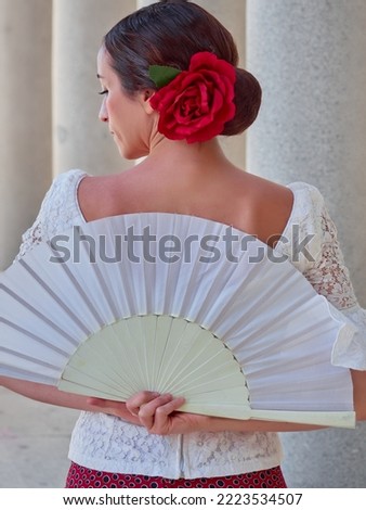 half body of flamenco dancer with fan on the back. profile view with red rose.