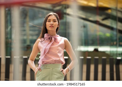 Half Body Portrait Of 20s Asian Woman Straight Black Hair Wear Formal Pink Green Dress Shirt. Female Feels Happy To Walk Street Outdoor For Shopping