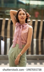 Half Body Portrait Of 20s Asian Woman Straight Black Hair Wear Formal Pink Green Dress Shirt. Female Feels Happy To Walk Street Outdoor For Shopping