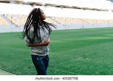 Half Body Portrait Of An African American Woman In Gray Hoodie Running Outdoors At Empty Stadium