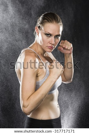 Similar – Close up front portrait of one young athletic woman in sportswear in gym over dark background, standing in boxing stance with hands and fists, looking at camera