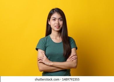 Half Body Shot Beauty Asian Confidence Teenager In Green Tee Shirt Folded Arms And Smiling Stand Isolated On Yellow Background In Studio.