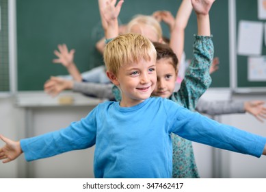 Half Body Shot Of A Cute Boy Doing An Stretching Exercise Inside The Classroom.