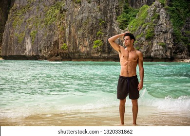 Half Body Shot Of A Handsome Young Man Standing On A Beach In Phuket Island, Thailand, Shirtless Wearing Boxer Shorts, Showing Muscular Fit Body