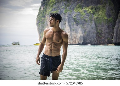 Half Body Shot Of A Handsome Young Man Standing On A Beach In Phuket Island, Thailand, Shirtless Wearing Boxer Shorts, Showing Muscular Fit Body