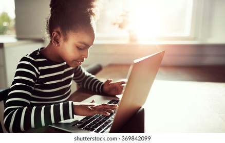 Half Body Shot Of A Pretty Black Girl Typing On The Keyboard Of Her Laptop Computer At The Wooden Table Near The Window.