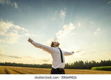 Half Body Shot of a Thankful Young Businessman Looking up the Sky with Wide Open Arms, Standing at the Open Field. - Shutterstock ID 300649826