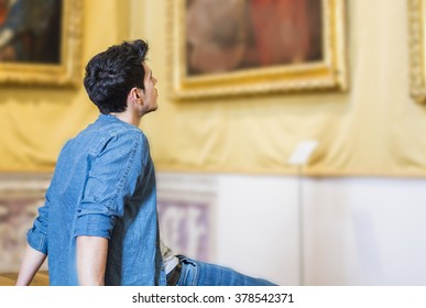 Half Body Shot of a Thoughtful Handsome Young Man, Looking At Painting Sitting on Bench Inside a Museum - Powered by Shutterstock