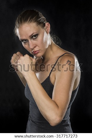 Similar – Close up front portrait of one young athletic woman in sportswear in gym over dark background, standing in boxing stance with hands and fists, looking at camera