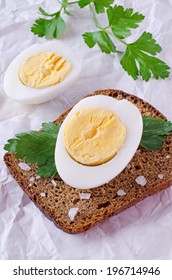 Half boiled egg lying on a piece of black bread 