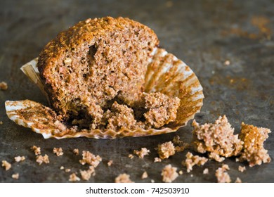 Half A Bran Muffin Close Up With Crumbs On A Rustic Surface.