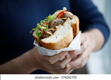 Half bread meatball sandwich on the hands on a man (Turkish street food)