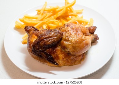 Half A Chicken Roasted With Fries On A Plate Above Bright Background