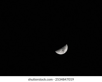 HALF CIRCLE MOON PHASE IN A STARLESS SKY