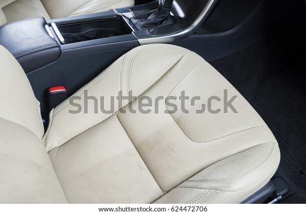 Half cleaned car seat with white\
leather vehicle interior. Example of car cleaning\
detailing