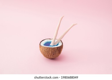 Half a coconut with blue water and plastic doll legs protruding from the coconut.