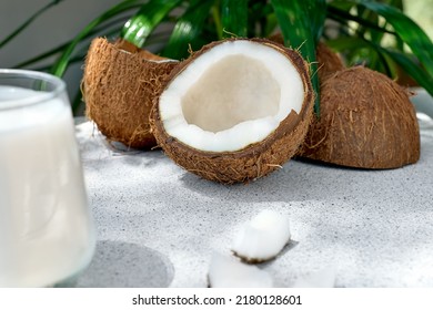 Half Of Coconut And Coconut Milk In Drinking Glass On Palm Leaf Background. Vegetable Milk, Lactose Free Non Dairy Healthy Drink. Vegan Food.