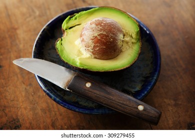 Half Cut Avocado On A Old Table With Old Fruit Knife.