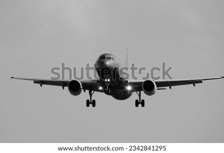 
half downside view black and white shot of a fling grey jet airplane landing on a flat clean
sky background with no sun and clouds neither (horizontal tile)